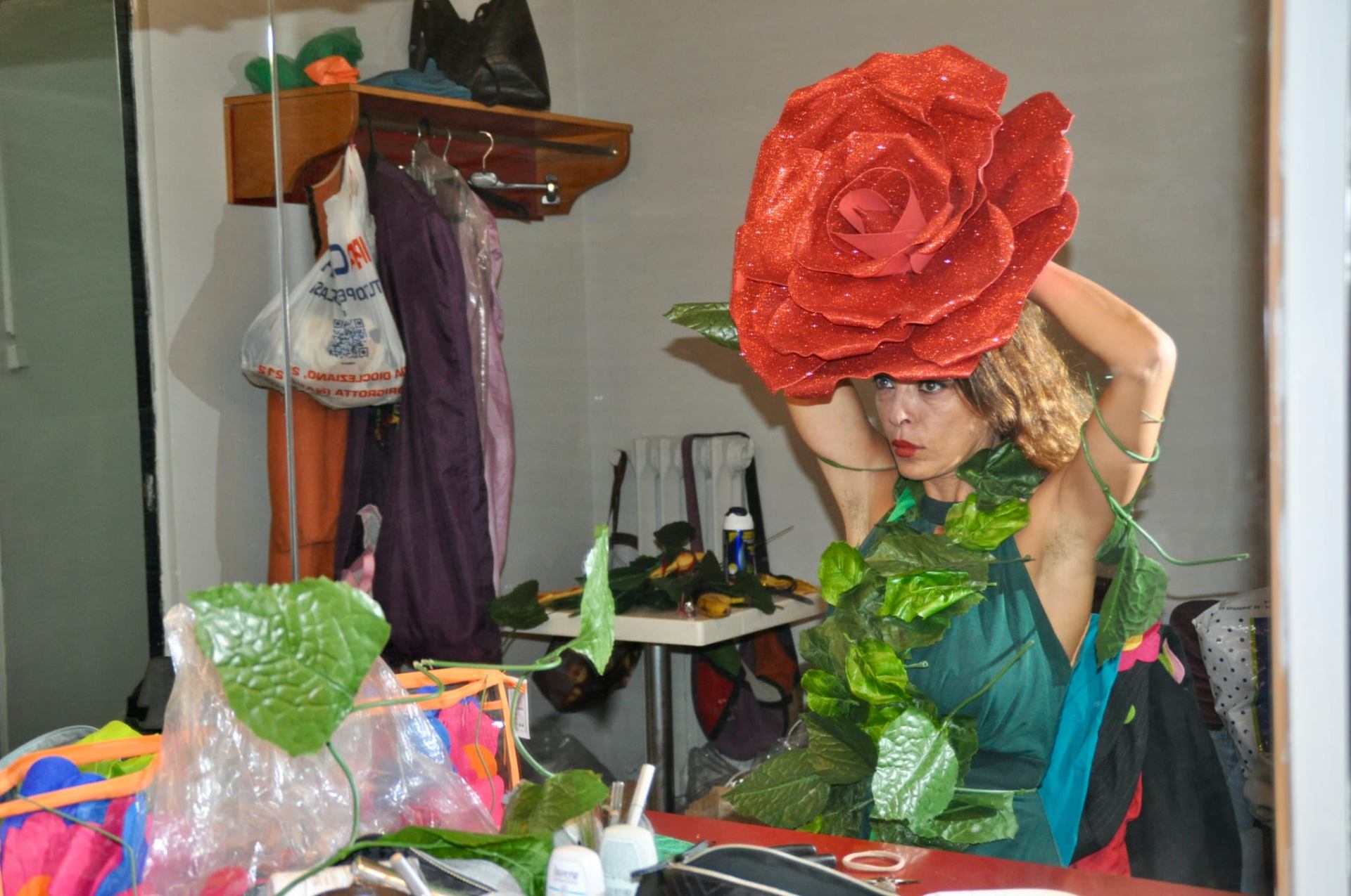 Artista con grande cappello a forma di rosa rossa in camerino