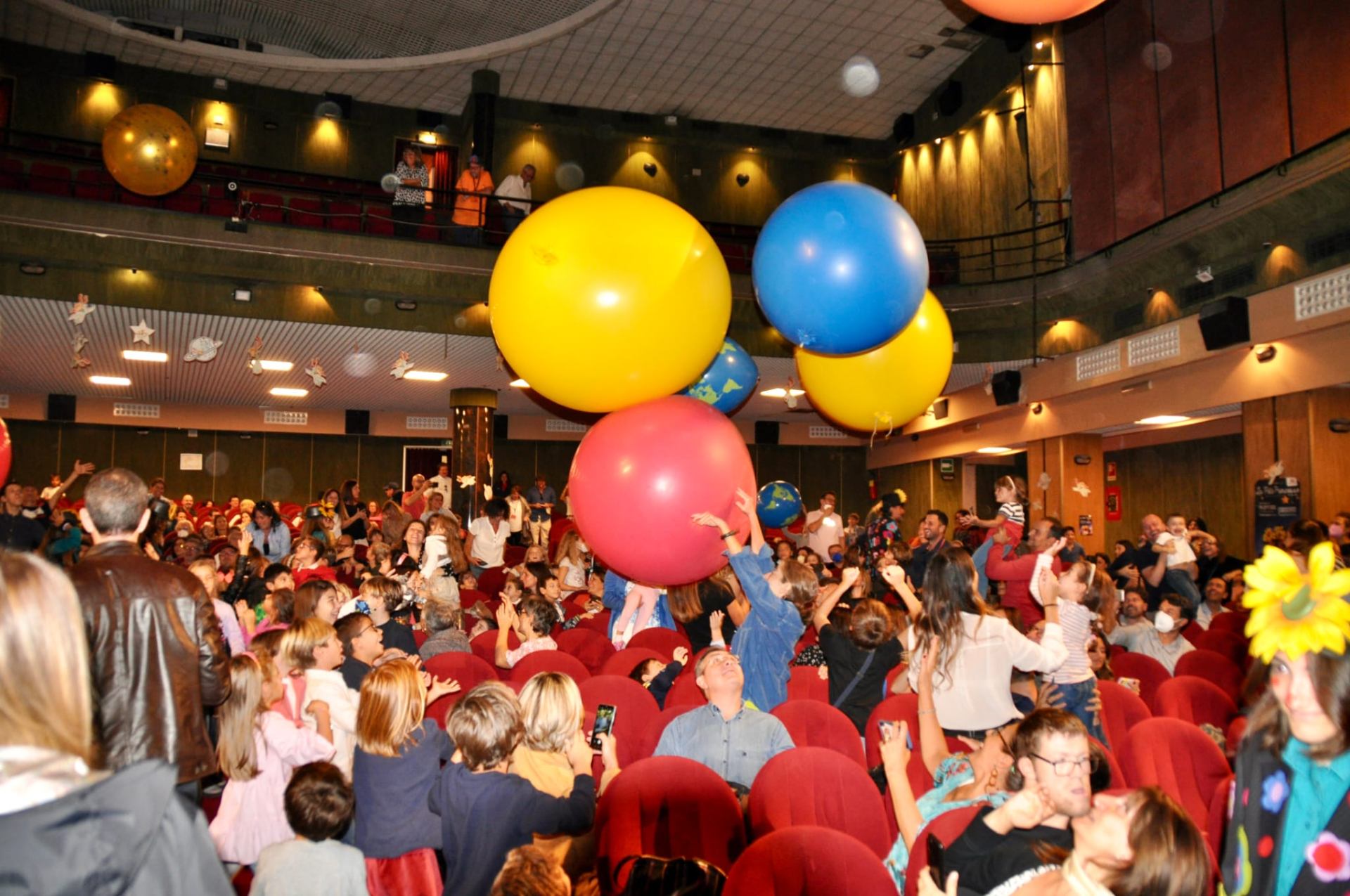 Pubblico in teatro che gioca con grandi palloni colorati