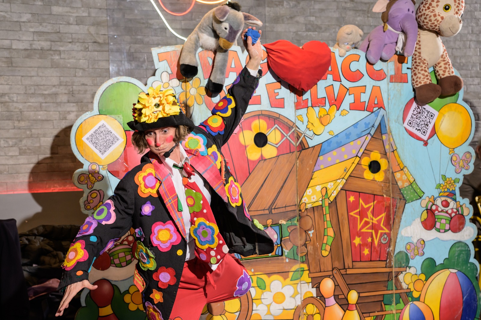 Pagliaccio con cappello di girasole in scena con peluche colorati