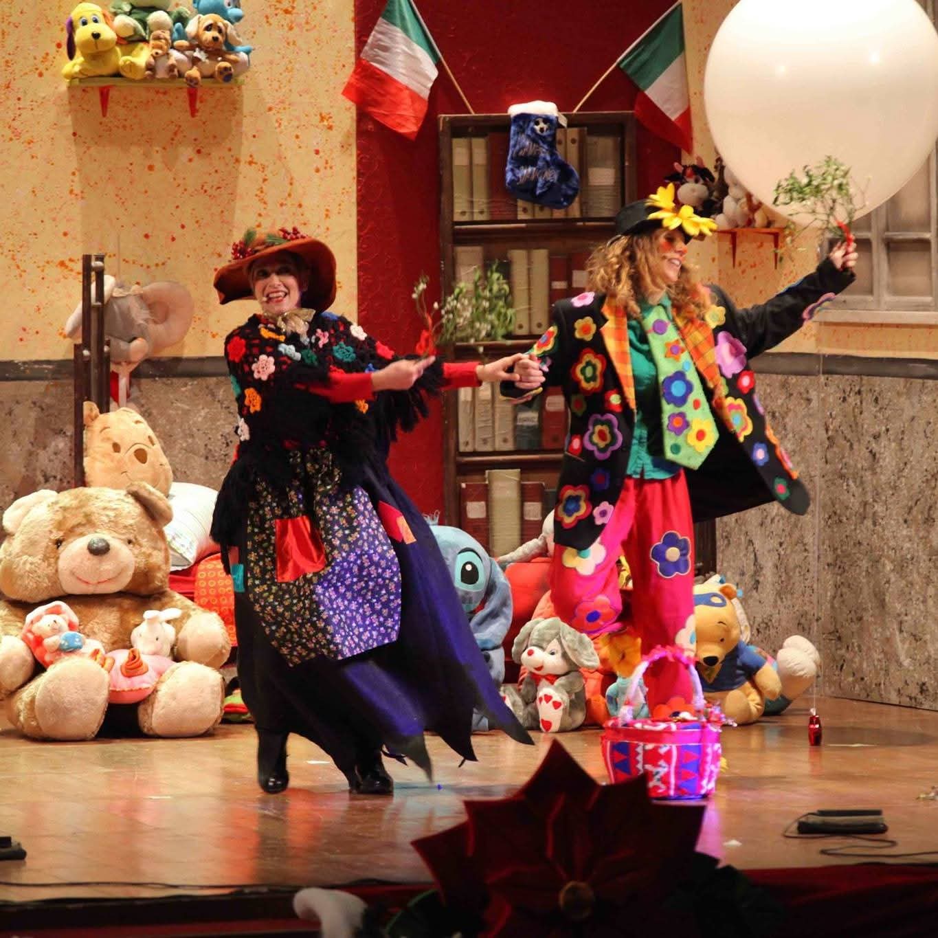 Due pagliacce ballano sul palco tra peluche e bandiere italiane
