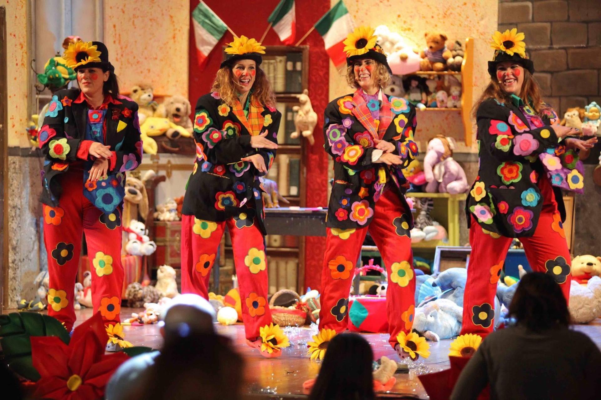 Quattro pagliacce con vestiti a fiori ballano sul palco
